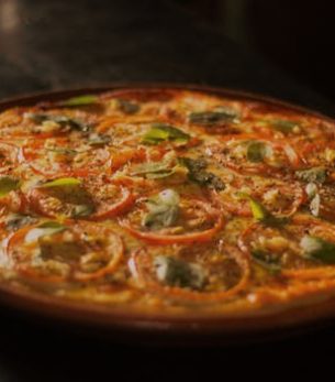 Close-up of a mouth-watering pizza topped with fresh basil, tomato, and mozzarella, capturing the essence of Italian cuisine.